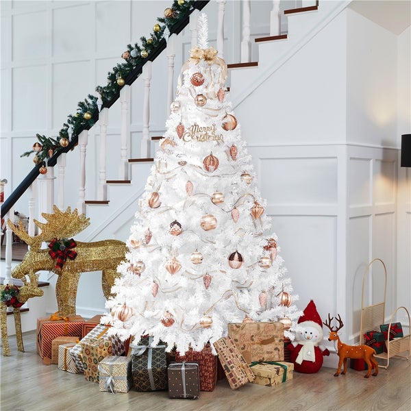 Weihnachtliche Dekoration mit weißem Weihnachtsbaum, Schmuck und Geschenken im hellen Treppenhaus.