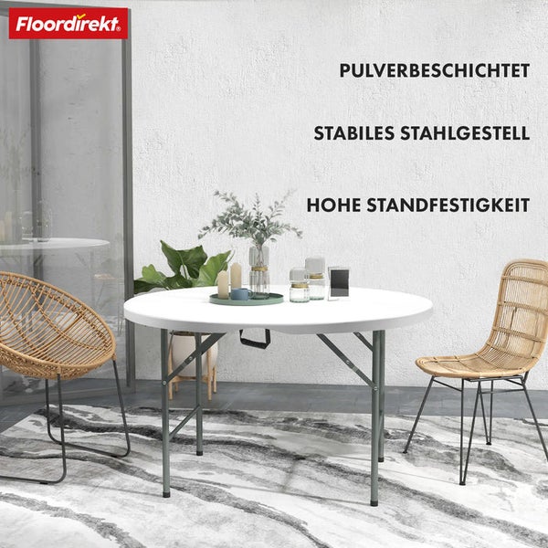 Floordirekt Logo. Runder weißer Klapptisch mit stabilem, pulverbeschichtetem Stahlgestell in moderner Umgebung mit Korbstühlen und Teppich.