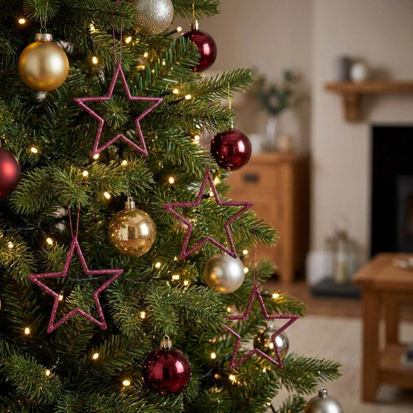 Weihnachtsbaum mit Dekoration aus Christbaumkugeln und glitzernden Sternen in einem Wohnzimmer mit Kamin.