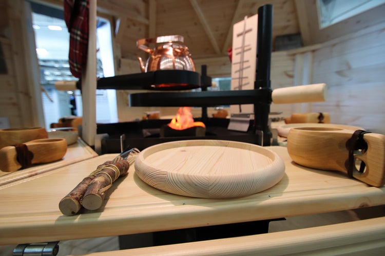 Holzteller, Holztasse und Kochfeuerstelle auf einem Tisch