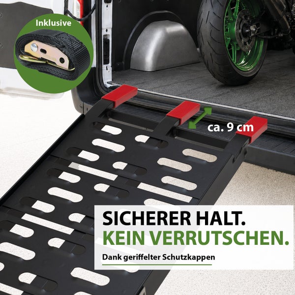 Schwarze Auffahrrampe aus Metall mit roten Schutzkappen an der Ladekante eines Fahrzeugs und inklusivem Spanngurt.