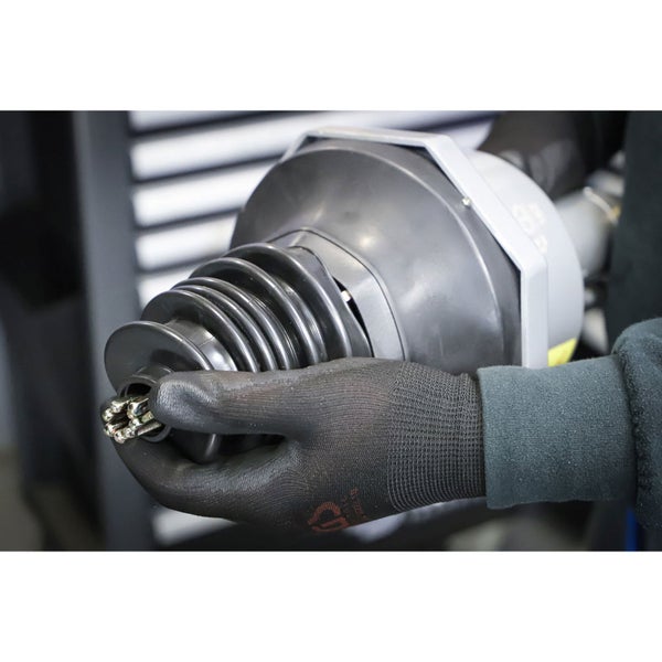 Eine Hand in Arbeitshandschuhen hält eine Rohrreinigungsspirale.