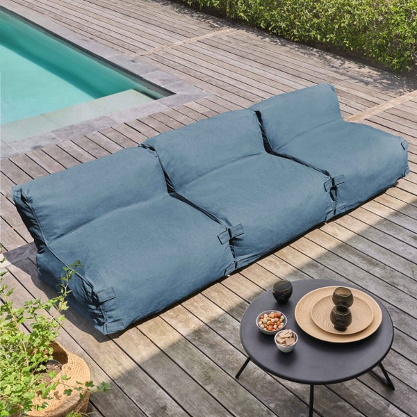 Blaues Outdoor-Lounge-Sofa auf einer Holzterrasse neben einem Pool mit Beistelltisch.