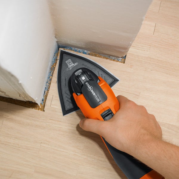 Eine oszillierende Multifunktionswerkzeug-Maschine wird zum Schleifen von Holzböden in der Ecke eines Raumes verwendet.