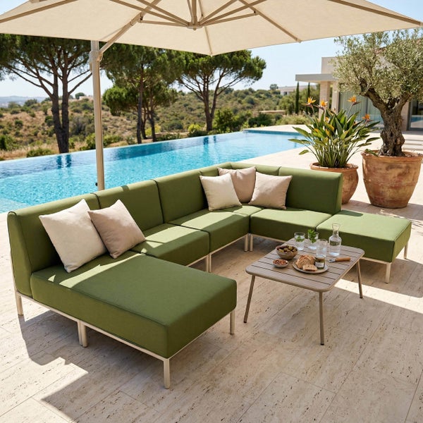 Modulares Garten-Ecksofa-Set mit grünen Polstern, Beistelltisch und Sonnenschirm auf einer Terrasse am Pool.