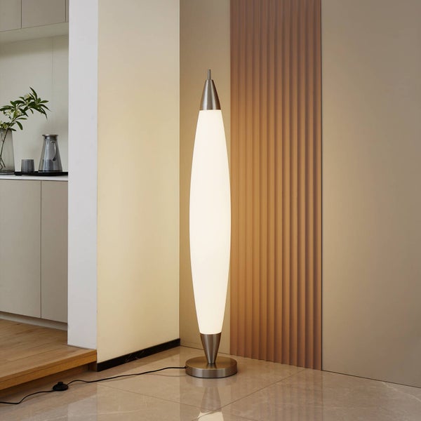 Moderne Stehleuchte mit schlankem, elliptischem weißem Leuchtkörper und rundem Metallsockel in einem hellen Raum neben einer strukturierten Wand.