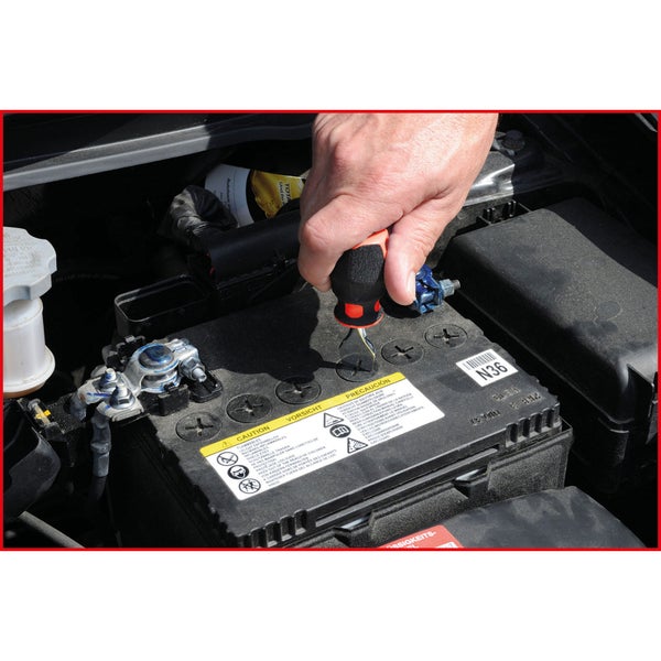 Eine Hand hantiert mit einem Schraubendreher an einer Autobatterie.