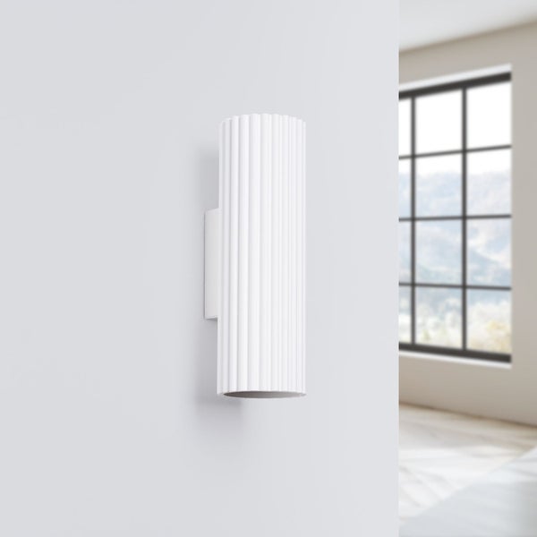 Weiße Wandleuchte mit geripptem Schirm in einem hellen Raum.
