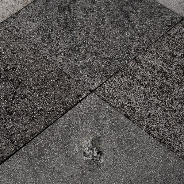 Quadratische Pflastersteine aus Beton mit rauer Oberfläche als Bodenbelag für den Garten.