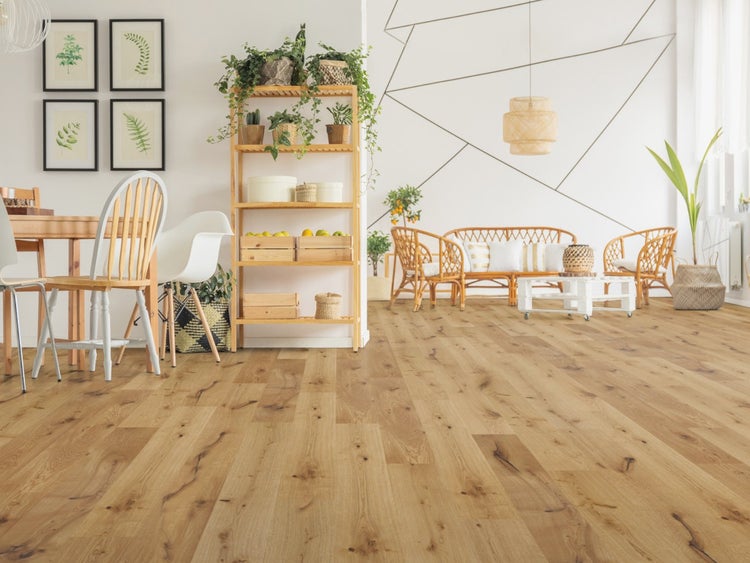 Heller Wohn- und Essbereich mit Landhausdielen-Bodenbelag in Eichenoptik, Rattanmöbeln, Holzregal und vielen Zimmerpflanzen.