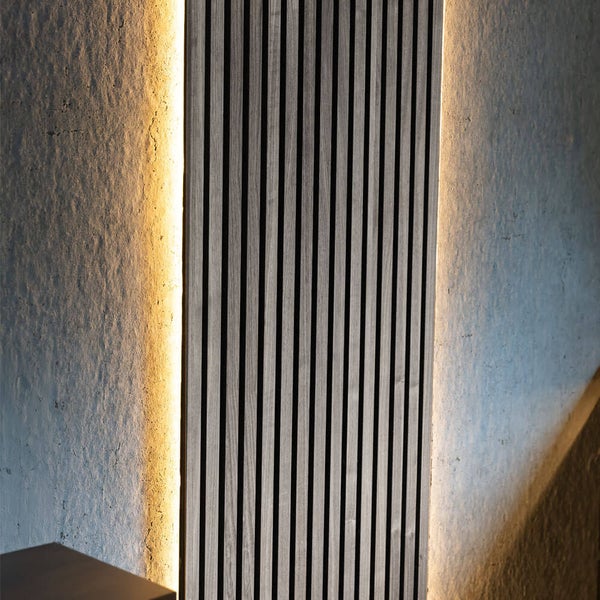 Vertikale Holzlamellenpaneele mit integrierter LED Beleuchtung an einer strukturierten Wand zur dekorativen Innenraumgestaltung.