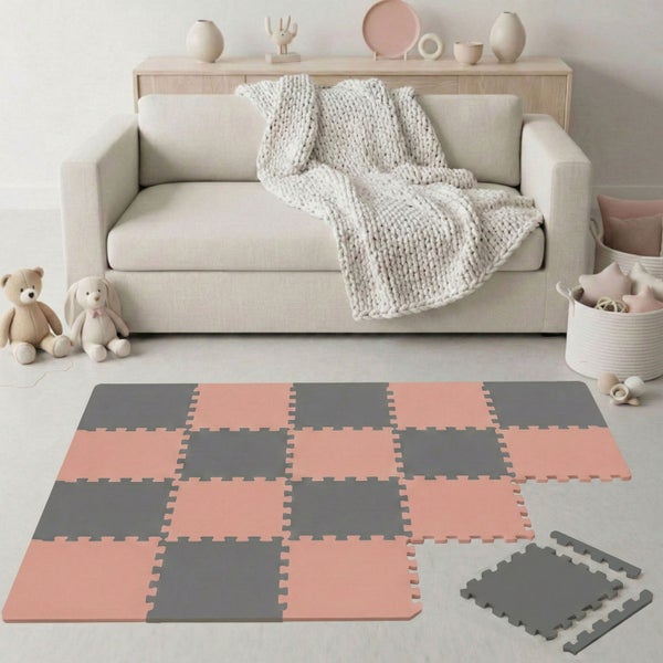 Schaumstoff-Spielmatte mit Puzzleteilen im Schachbrettmuster in Rosa und Grau in einem hellen Kinderzimmer mit Sofa.