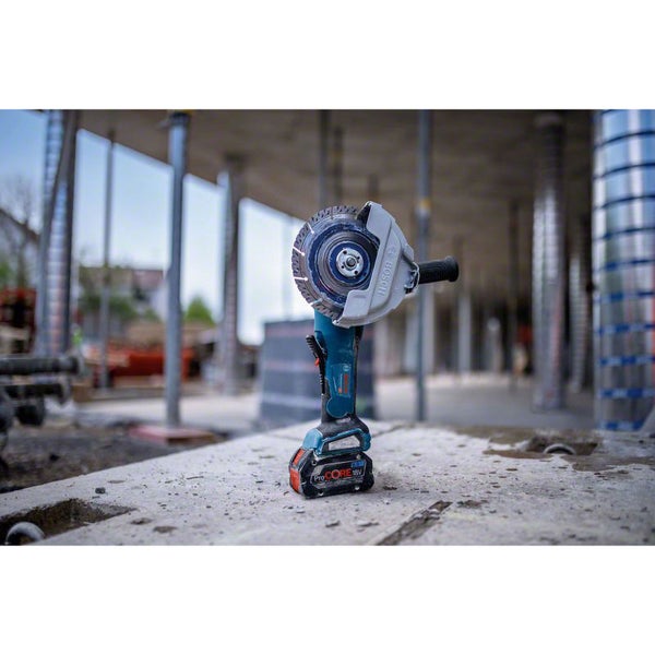 Bosch Professional Akku-Winkelschleifer mit ProCORE 18 Volt Akku auf einer Betonplatte auf einer hellen Baustelle.