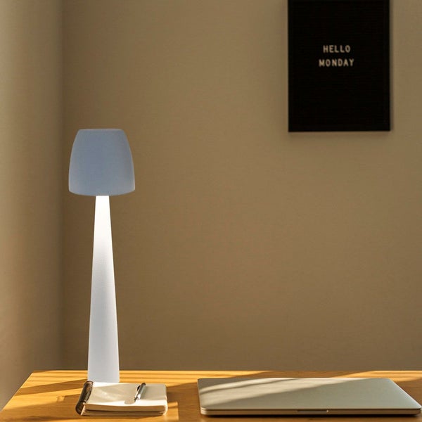 Schreibtisch mit Lampe, Notizbuch, Stift und Laptop.