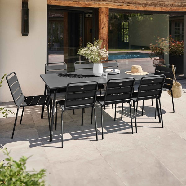 Moderner rechteckiger Gartentisch mit sechs passenden Metallstühlen in Lamellen-Optik auf einer hellen, organisierten Terrasse.