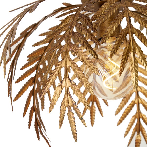 Detail einer Deckenleuchte mit goldenen Metallblättern im botanischen Design und einem sichtbaren, leuchtenden Filament-Leuchtmittel.
