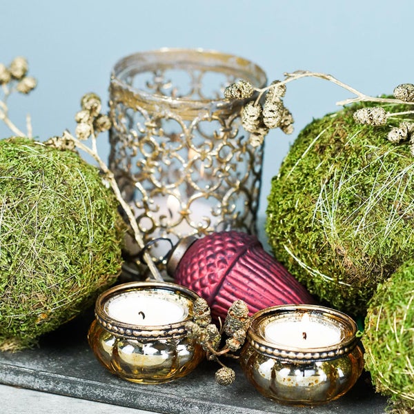 Dekorative Anordnung mit Mooskugeln, Windlicht, Teelichtern und Ornamenten auf einem Tablett