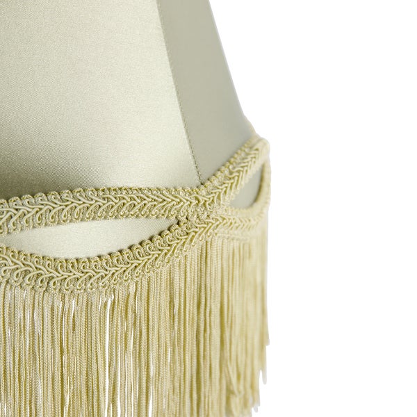 Detailansicht eines Lampenschirms mit dekorativer Borte und langen Fransen aus Stoff.