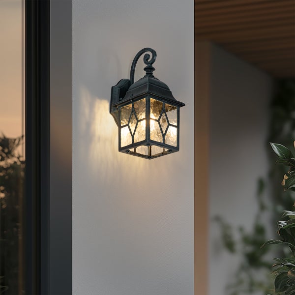 Klassische Außenwandleuchte in Schwarz mit strukturiertem Glas und dekorativem Wandarm, montiert und eingeschaltet.