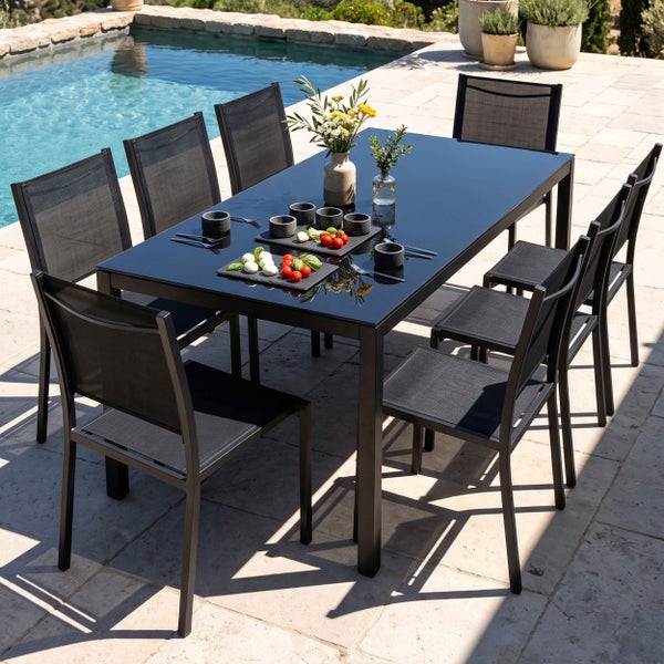 Modernes Gartenmöbel-Set mit rechteckigem Tisch mit schwarzer Glasplatte und acht Stühlen mit schwarzem Netzgewebe auf einer Terrasse am Pool.
