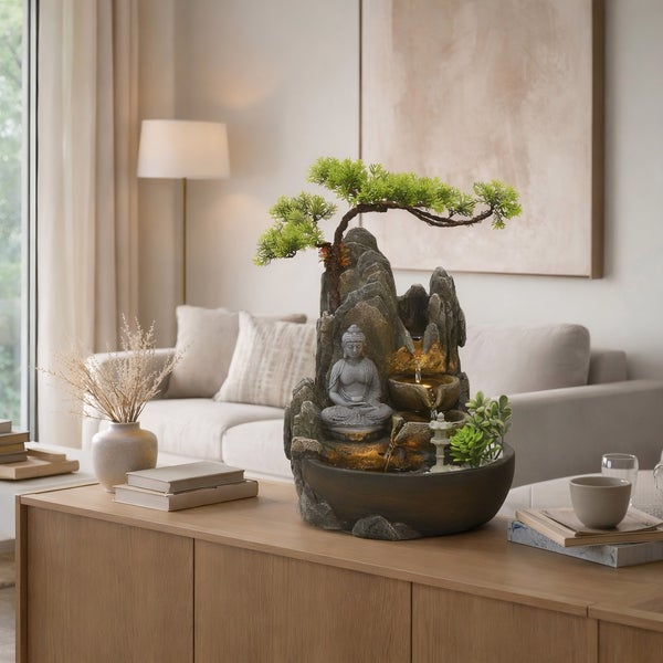 Zimmerbrunnen mit Buddha-Figur, Bonsai-Baum und LED-Beleuchtung in Steinoptik auf einem Sideboard in einem hellen Wohnzimmer.