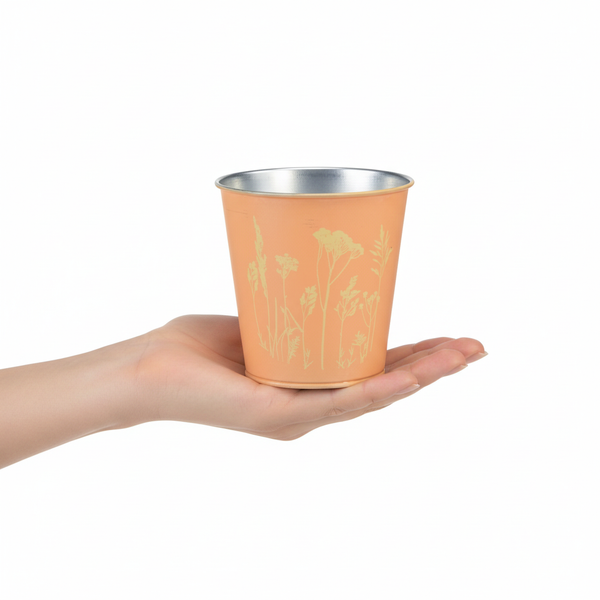 Kleiner Zinkübertopf mit Gräser-Motiv in einer Hand gehalten.