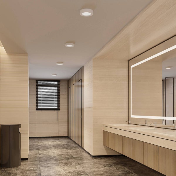 Moderne Badezimmerbeleuchtung mit runden Einbaustrahlern, Holzoptik, großer Spiegel mit Lichtrahmen und Steinfußboden.