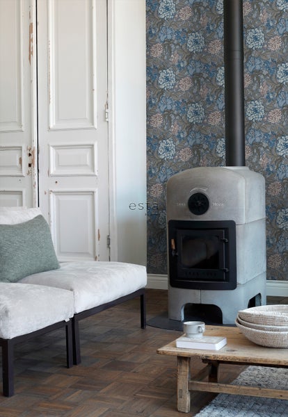 Wohnraum mit Kaminofen, Sofa und geblümter Tapete für eine gemütliche Atmosphäre.