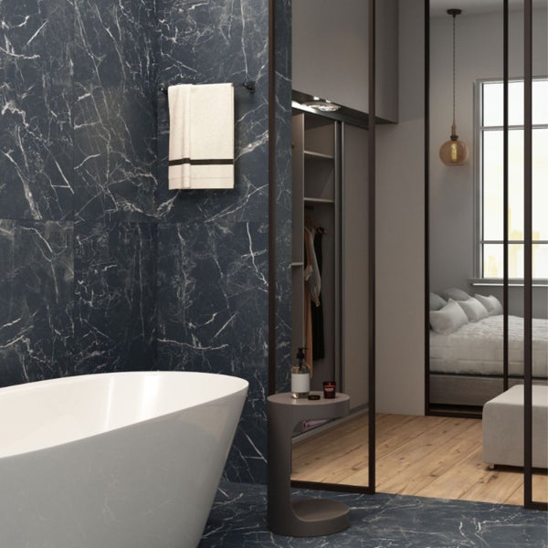 Badezimmer mit Badewanne, Handtuch und gefliester Wand in Marmoroptik