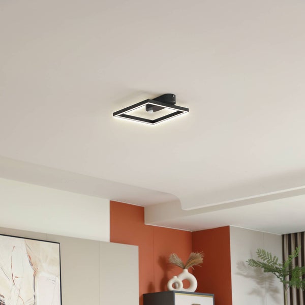 Moderne quadratische LED-Deckenleuchte in Schwarz an einer weißen Decke in einem hellen, modern eingerichteten Raum mit farbigen Akzentwänden.