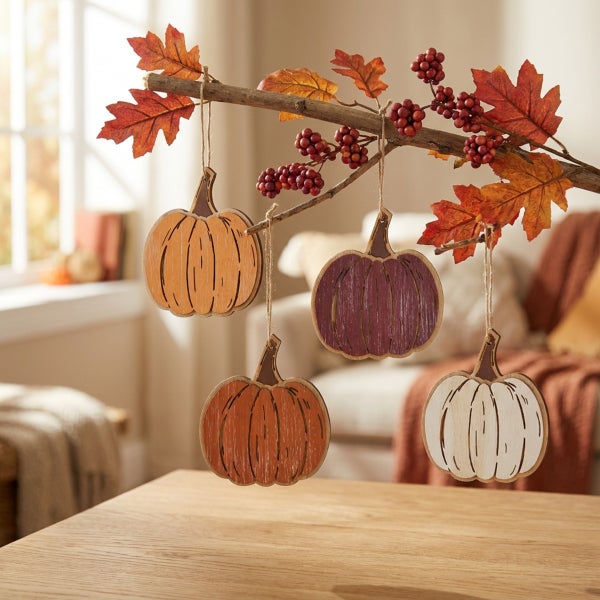 Herbstliche Deko zum Aufhängen, vier flache Kürbis-Anhänger aus Holz an einem Ast mit Kunstblättern und Beeren dekoriert