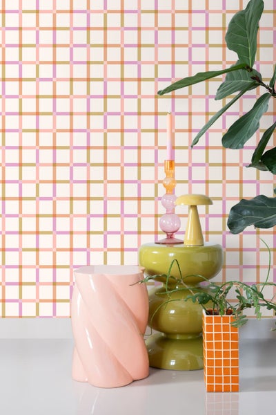 Vliestapete mit Karomuster in einem modern eingerichteten Raum mit dekorativen Beistelltischen, einer Lampe und Zimmerpflanzen.