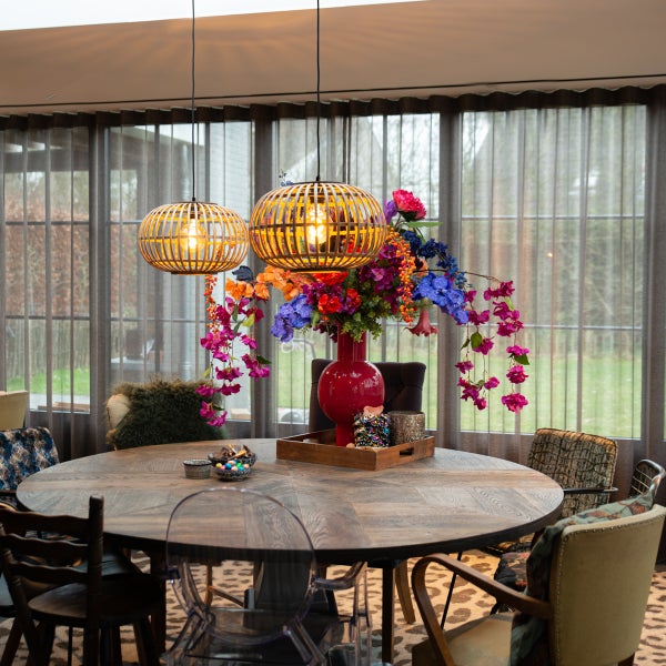 Esszimmer mit rundem Holztisch, Stühlen und zwei hölzernen Hängeleuchten über dem Tisch.