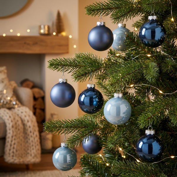 Weihnachtsbaum mit blauen Weihnachtskugeln in verschiedenen Blautönen dekoriert, im Hintergrund ein gemütliches Wohnzimmer mit Kamin.