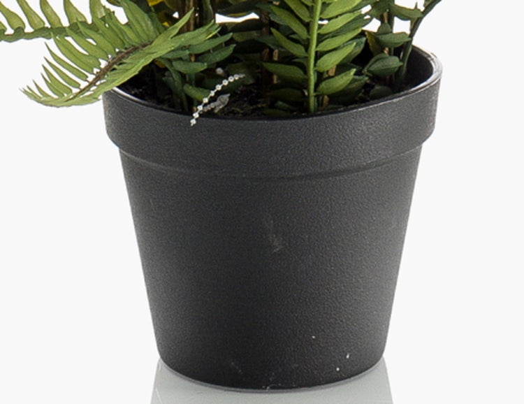 Künstliche Alocasia Pflanze im schwarzen Topf mit großen grünen Blättern und braunen Stämmen.