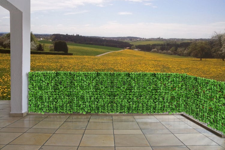 Dekorative grüne Blättermatte als Sichtschutz auf einem Balkon mit Fliesenboden.