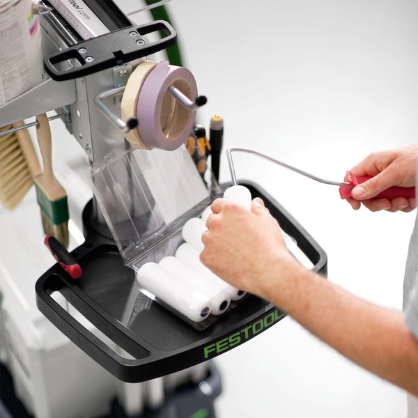 Festool Arbeitsplatz für Malerarbeiten mit Farbwalzen, Pinseln und Abdeckband. Ein Anwender steckt eine Walze auf einen Farbrollerbügel.