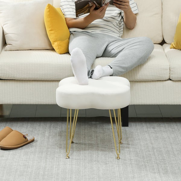 Szene mit einer Person, die ein Buch liest, mit den Füßen auf einem weißen, blütenförmigen Hocker mit goldenen Beinen.