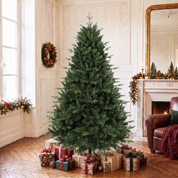Familie feiert Weihnachten vor einem kuenstlichen Tannenbaum in einem wohnlichen Raum mit Kamin.