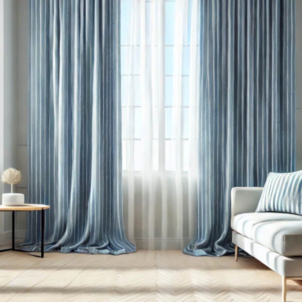 Helles Wohnzimmer mit blau gestreiften Gardinen und weißen, transparenten Vorhängen vor einem Fenster