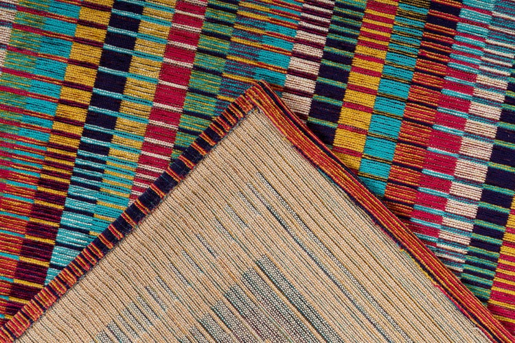 Bunt gewebter Teppich mit geometrischem Streifenmuster und beiger Rückseite an der Ecke.