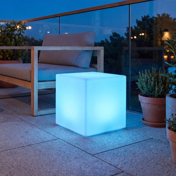 Beleuchteter LED Sitzwürfel als Gartenmöbel auf einem Balkon am Abend.