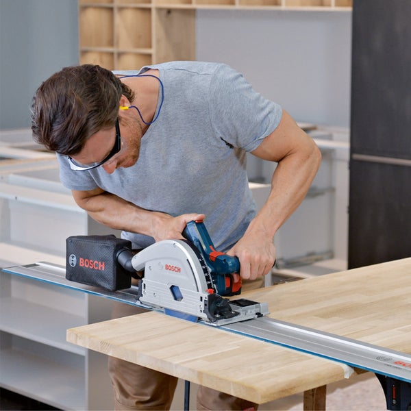 Mann sägt Holzplatte mit Handkreissäge von Bosch