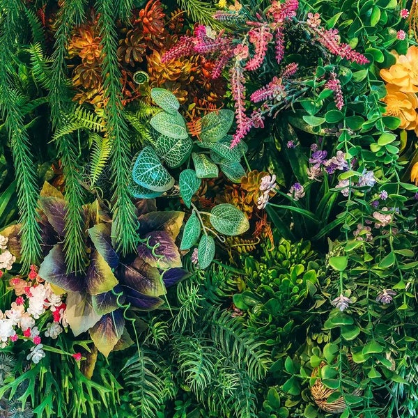Künstliche Pflanzenwand mit Blättern, Farnen, Sukkulenten und kleinen Blüten für eine dichte, realistische vertikale Begrünung.