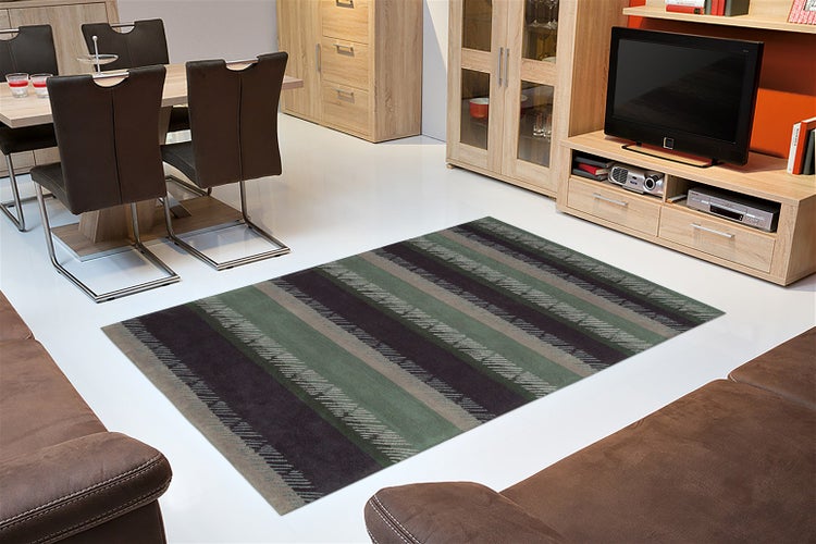 Ein moderner Wohnzimmerteppich mit gestreiftem Muster liegt auf dem Boden zwischen einem Essbereich mit Stühlen und einem Sofa.