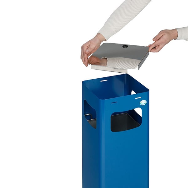 Eine Person hält den silbernen Metalldeckel über einen blauen VAR Abfallbehälter aus Metall.