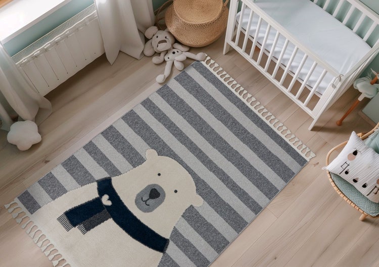 Kinderteppich mit Eisbär Motiv und Streifenmuster auf Holzboden in einem hell eingerichteten Kinderzimmer.