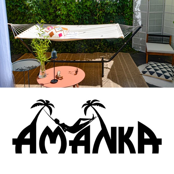 Hängematte mit Metallgestell auf einer hellen Terrasse mit Beistelltischen, Pflanzen, Teppich und Gartenstuhl. AMANKA Logo.
