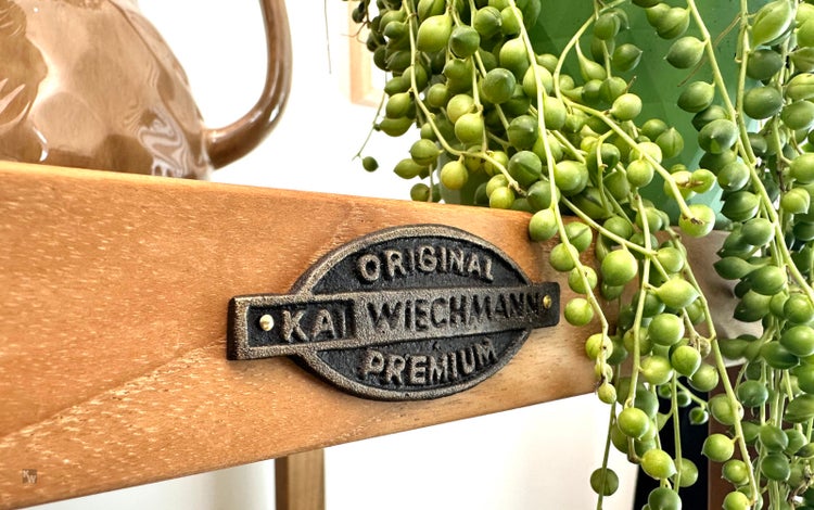 Detailansicht eines Kai Wiechmann Premiumschilds auf einem Holzregal mit Pflanze
