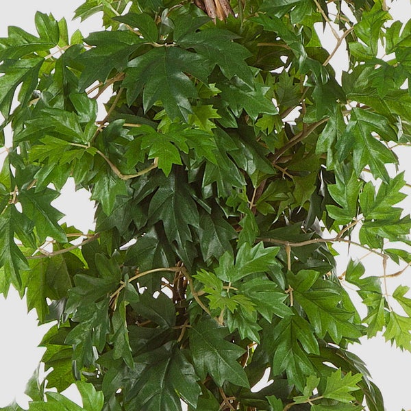 Nahaufnahme einer künstlichen Pflanze mit dichten, gezackten grünen Blättern.